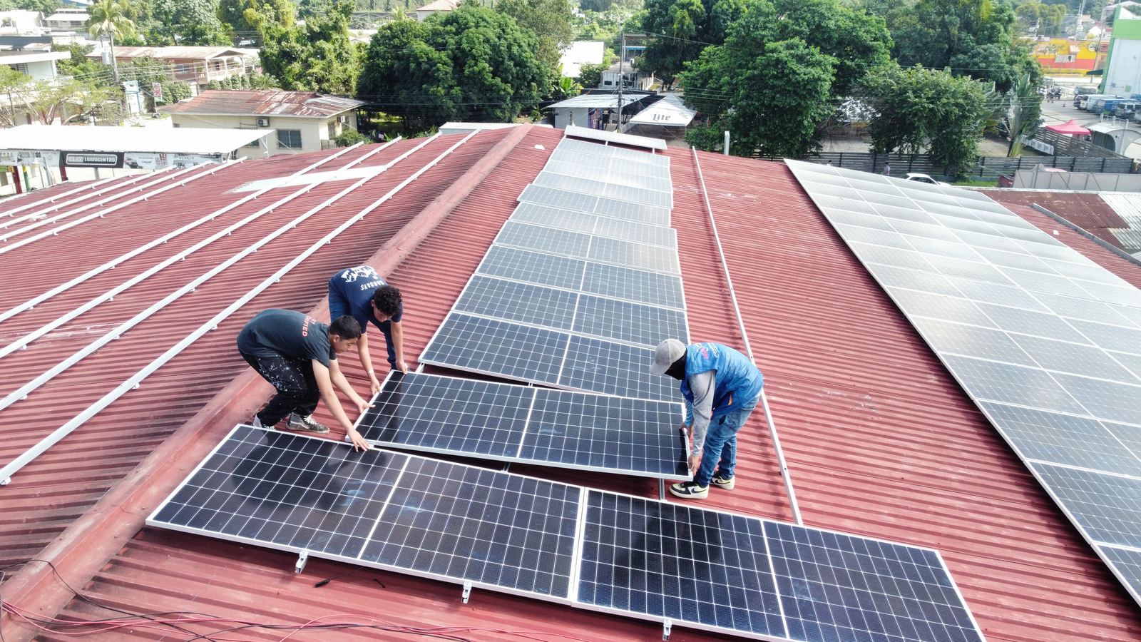 Técnicos colocando paneles solares sobre un techo de lámina roja